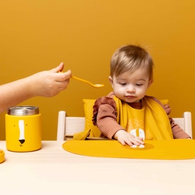 Copo térmico amarelo e criança com babete amarelo a ser alimentada