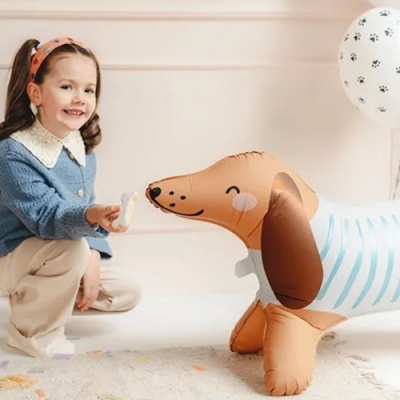 Menina sentada ao lado de balão insuflável em forma de cão