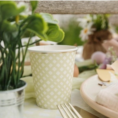 Copo de papel bege com padrão quadriculado numa mesa decorada
