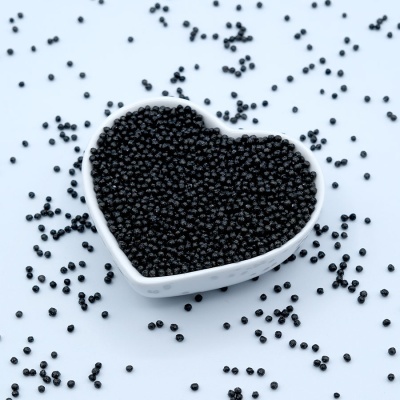 Recipiente em forma de coração com pequenas esferas pretas e esferas espalhadas ao redor