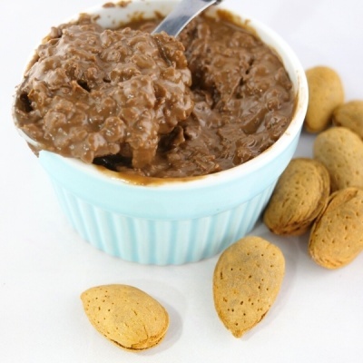 Taça azul com doce cremoso castanho e amêndoas com casca clara