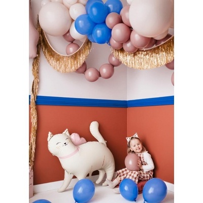 Decoração com balões azuis, rosa, branco e dourado, figura de gato branco e figura de boneca numa superfície branca