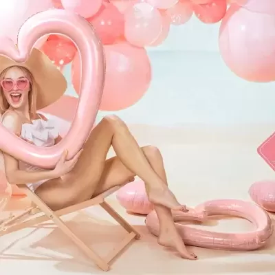 Mulher com balão coração rosa em espreguiçadeira rodeada de balões e sinal bride cor de rosa
