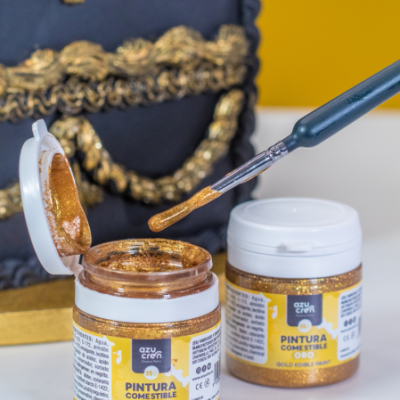 Frascos de tinta comestível dourada da marca azu cre8 com pincel e fundo azul e dourado.