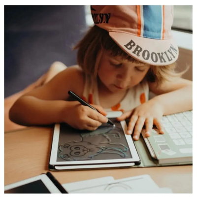 Criança desenhando num tablet digital com boné 'BROOKLYN'