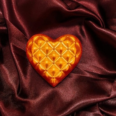 Coração decorativo laranja dourado sobre tecido bordô acetinado