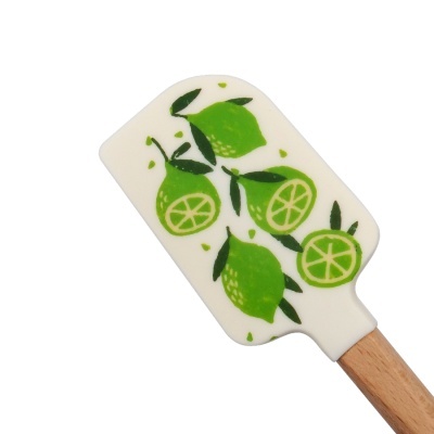 Espátula de cozinha branca com limões verdes e cabo de madeira