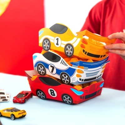 Caixas de papelão em forma de carros de corrida com snacks laranja