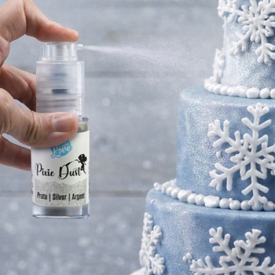 Frasco de glitter prateado a ser pulverizado sobre bolo azul decorado com flocos de neve brancos