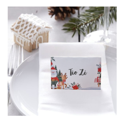 Prato branco com guardanapo e cartão de lugar de Natal 'Tio Zé' e árvore de Natal ao fundo