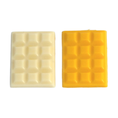 Dois sabonetes em forma de tablete de chocolate branco e amarelo com textura quadriculada.