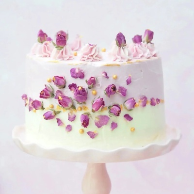 Bolo decorado com flores secas e chantilly rosa num suporte branco
