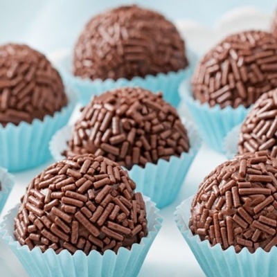 Brigadeiros de chocolate em forminhas azuis sobre prato branco