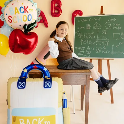 Menina numa sala de aula com mochila inflável e balões decorativos BACK TO SCHOOL