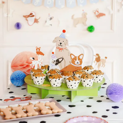 Cupcakes decorados com cobertura chocolate e figuras de cães, bolachas em forma de ossos, bolas de papel coloridas e decoração temática de cães