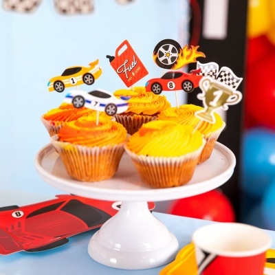 Cupcakes com cobertura amarela e laranja e decoração de carros de corrida em toppers numa base branca