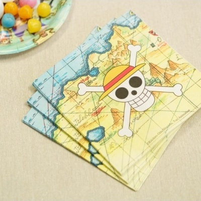 Guardanapos com estampa de mapa e caveira de pirata ao lado de prato com doces coloridos