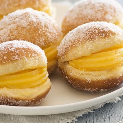 Pão doce recheado com creme e coberto com açúcar em prato branco