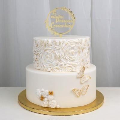 Bolo de dois andares branco com decoração de rosas douradas e topper 'A minha Primeira Comunhão'
