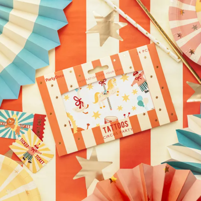 Artigos festivos coloridos em cima de mesa com toalha às riscas cor-de-rosa e branca