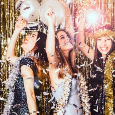 Três mulheres a celebrar com balões e decoração dourada metálica