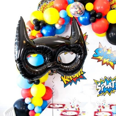 Máscara preta de balão em forma de máscara de super-herói e guirlanda de balões coloridos numa festa de aniversário