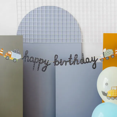 Decoração de aniversário com balões e faixa 'happy birthday' numa parede colorida