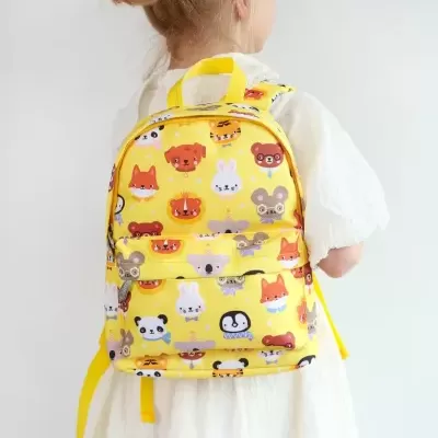 Mochila infantil amarela com animais cartoon coloridos numa criança
