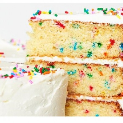 Bolo branco com cobertura creme e confetes coloridos cortado ao meio