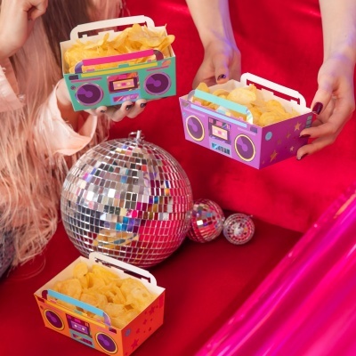 Três caixas coloridas em forma de rádio retro com batatas fritas e bolas de discoteca ao fundo.