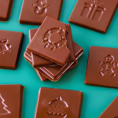 Quadrados de chocolate ao leite com desenhos natalícios sobre fundo azul