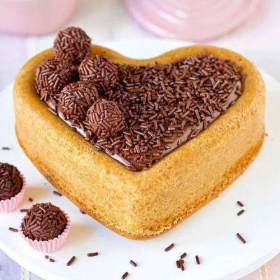 Bolo coração coberto com chocolate e brigadeiros com granulados