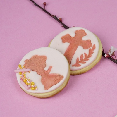 Dois biscoitos decorados com glacê branco e figuras em castanho sobre fundo rosa