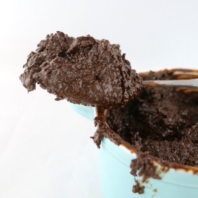 Colher com creme castanho escuro retirada de recipiente azul claro