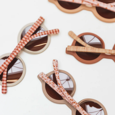 Óculos de sol redondos com armações bege, castanho e rosa e hastes estampadas.