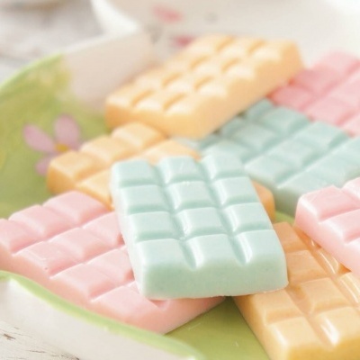 Barras de chocolate coloridas em tons pastéis num prato com padrão floral