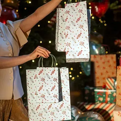 Duas sacolas de papel de presente decoradas com bengalas doces vermelhas e bolinhas em ambiente natalício
