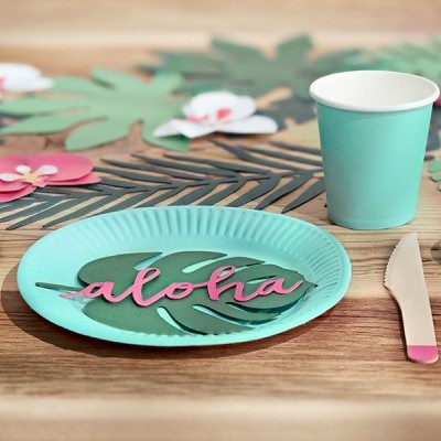 Conjunto de festa com pratos e copos azuis turquesa, talheres de madeira com pontas cor de rosa e decoração tropical de papel.
