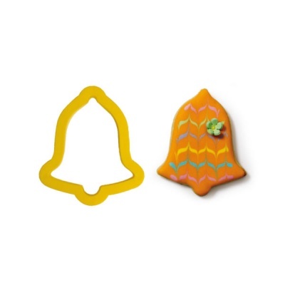 Cortador de biscoitos em forma de sino amarelo e biscoito decorado laranja com padrões e flor verde