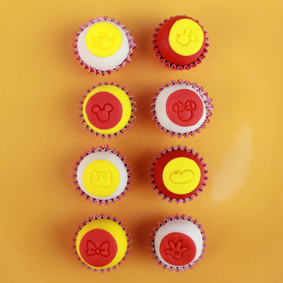 Oito cupcakes coloridos com símbolos em relevo sobre fundo laranja