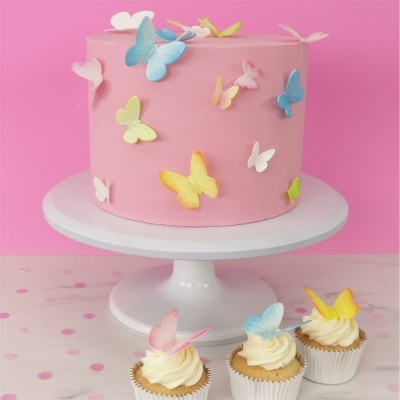 Bolo rosa com borboletas coloridas em suporte branco e três cupcakes com borboletas