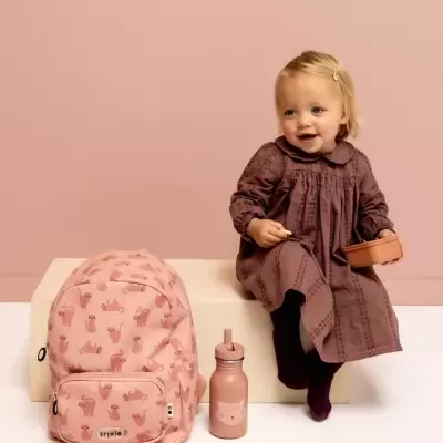 Mochila rosa com padrão de lontras e criança com vestido castanho