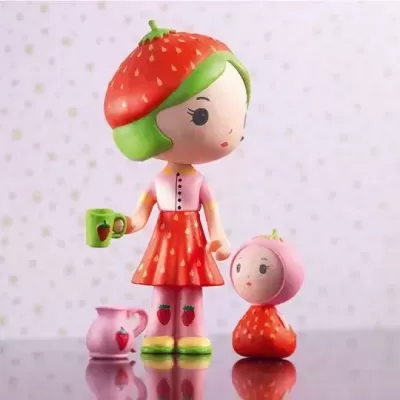 Duas figuras de plástico tematizadas como morangos e um jarro cor-de-rosa sobre superfície reflexiva