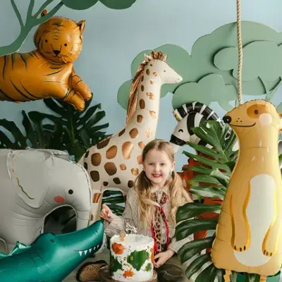 Criança entre balões de animais de safari com bolo e decoração temática