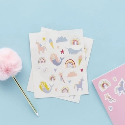 Autocolantes coloridos com desenhos de arco-íris, unicórnios, sereias, nuvens e estrelas sobre fundo azul claro.