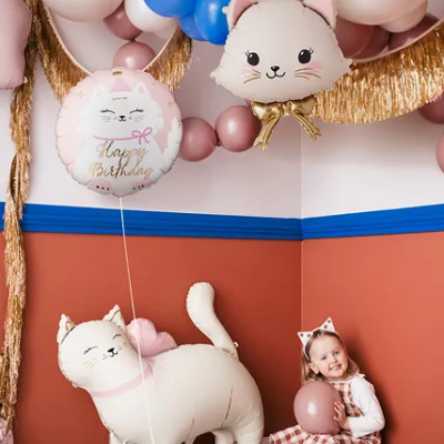 Decoração de festa com balões e criança com roupa rosa e branca sentada no chão