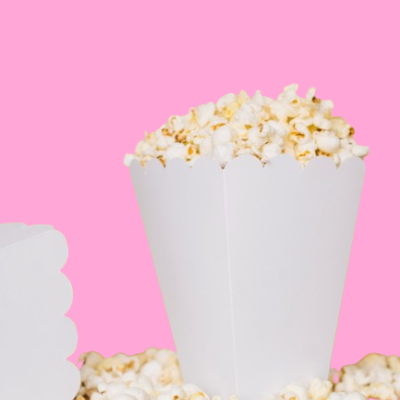 Caixa branca de papel cheia de pipoca com bordas onduladas sobre fundo cor-de-rosa