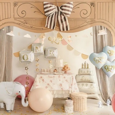 Decoração de festa infantil com balões, bolo decorativo, elefante de pelúcia, bolas e mesa com toalha