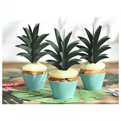 Três cupcakes decorados com folhas verdes em forma de abacaxi em forminhas azuis sobre mesa de madeira