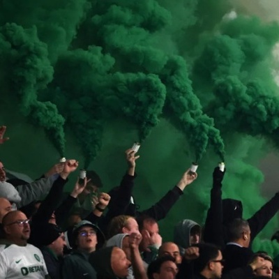 Pessoas a libertar fumo verde numa multidão de adeptos